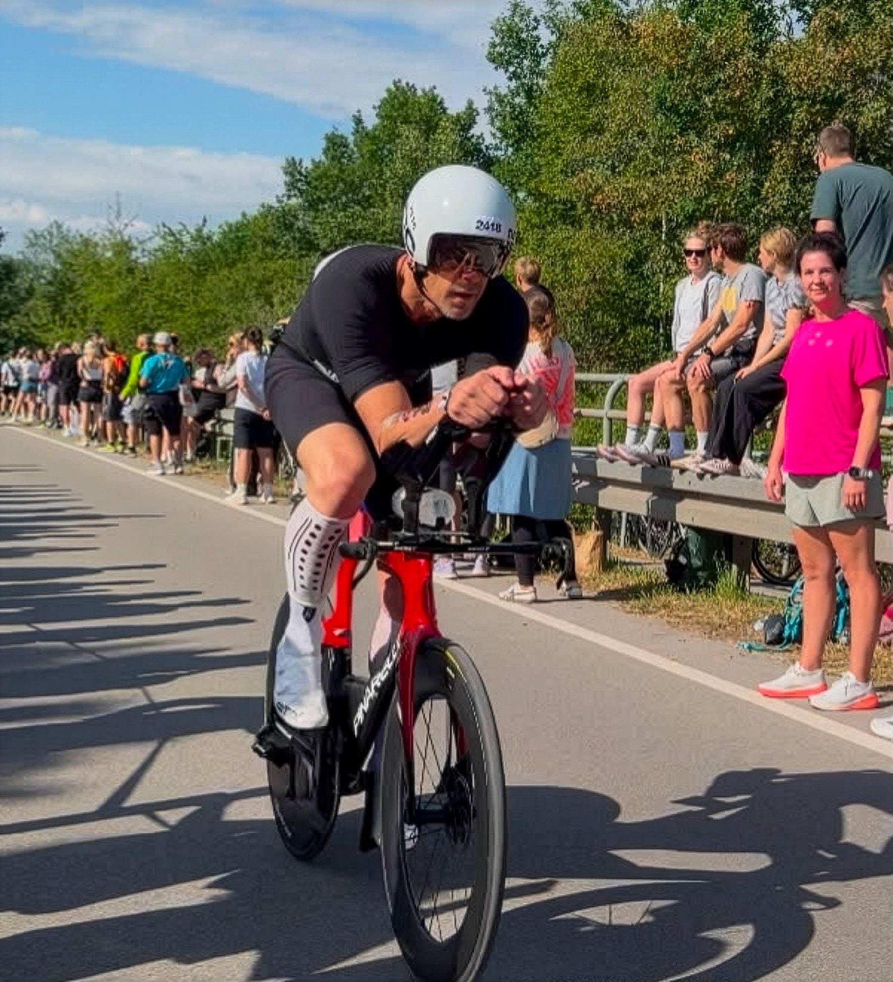 Menno Dellisse racing on the bike leg of a triathlon, with spectators